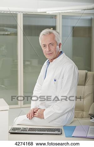 Doctor sitting on desk View Large Photo Image Stock Photo - Doctor sitting on desk . Fotosearch