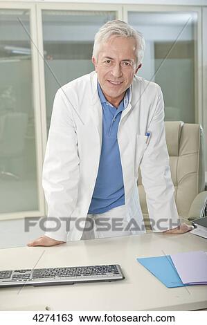 Doctor standing behind desk View Large Photo Image Stock Image - Doctor standing behind desk . Fotosearch