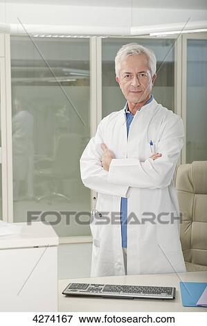 Doctor standing behind desk View Large Photo Image Stock Photo - Doctor standing behind desk . Fotosearch