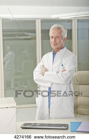 Doctor standing behind desk View Large Photo Image Stock Photograph - Doctor standing behind desk . Fotosearch