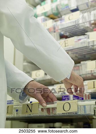 Stock Photography - Doctor taking medicine from rack . Fotosearch