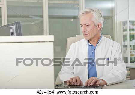 Doctor using computer at desk View Large Photo Image Picture - Doctor using computer at desk . Fotosearch