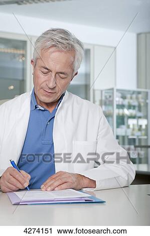 Stock Image - Doctor writing at desk . Fotosearch