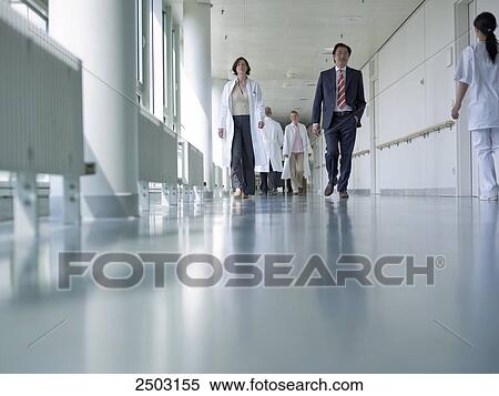 Doctors and businessman walking in corridor of hospital View Large Photo Image Stock Photography - Doctors and businessman walking in corridor of hospital . Fotosearch