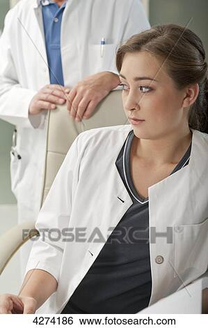 Stock Photograph - Doubtful doctor's assistant turning round . Fotosearch