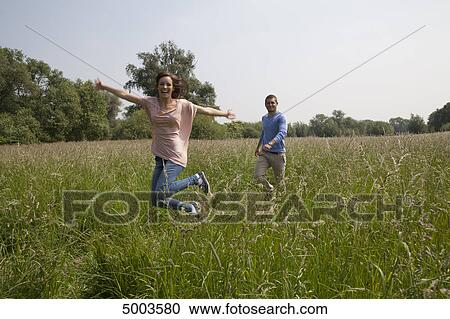 Stock Image - Enthusiastic young couple in field . Fotosearch