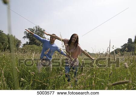 Stock Photo - Enthusiastic young couple in field . Fotosearch