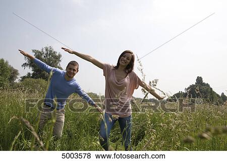 Enthusiastic young couple in field View Large Photo Image Stock Photo - Enthusiastic young couple in field . Fotosearch