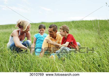 Stock Photo - Family sitting in grass . Fotosearch