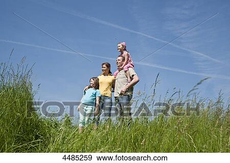 Stock Photo - Family standing on a meadow . Fotosearch