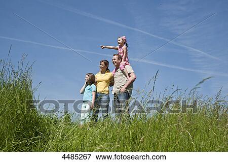 Stock Photo - Family standing on a meadow . Fotosearch
