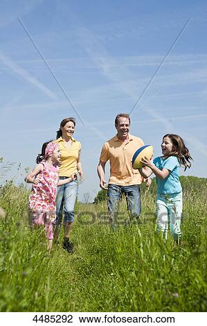 Stock Image - Family throwing football on a meadow . Fotosearch