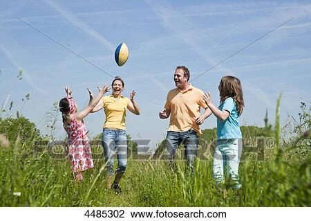 Stock Image - Family throwing football on a meadow . Fotosearch