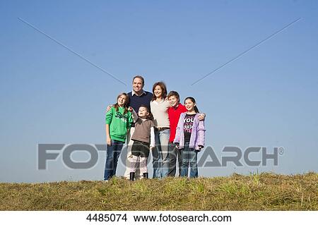 Family with four kids standing on a meadow View Large Photo Image Picture - Family with four kids standing on a meadow . Fotosearch