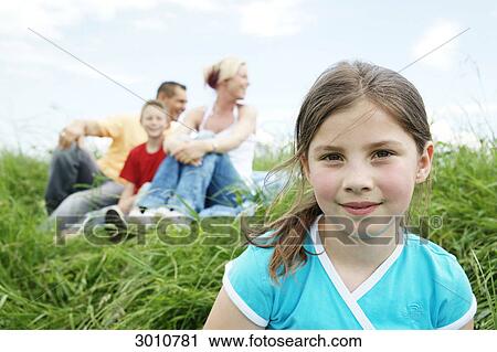 Stock Image - Family with two children sitting on grass . Fotosearch