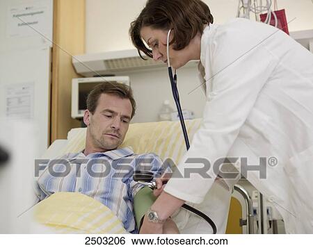 Stock Photograph - Female doctor examining male patient . Fotosearch