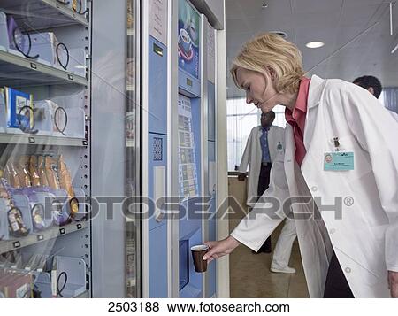 Stock Photo - Female doctor taking coffee from vending machine . Fotosearch