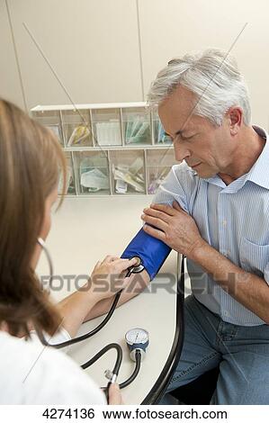 Stock Photograph - Female doctor taking patient's blood pressure . Fotosearch