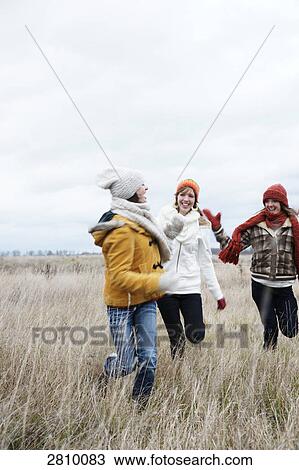 Female friends enjoying in field in warm clothing View Large Photo Image Stock Image - Female friends enjoying in field in warm clothing . Fotosearch