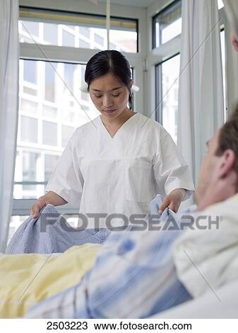 Female nurse changing bed sheet of patient's bed View Large Photo Image Stock Image - Female nurse changing bed sheet of patient's bed . Fotosearch