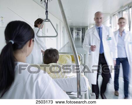 Stock Image - Female nurse pushing patient on gurney . Fotosearch