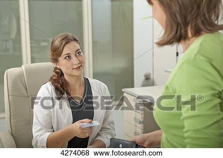 Stock Photo - Female patient and doctor's assistant at desk with health insurance card . Fotosearch