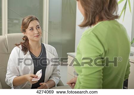Stock Photo - Female patient and doctor's assistant at desk with ten Euro . Fotosearch