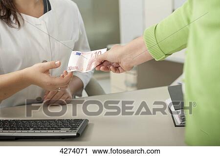 Female patient handing over ten Euro to doctor's assistant at desk View Large Photo Image Stock Image - Female patient handing over ten Euro to doctor's assistant at desk . Fotosearch