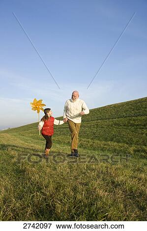 Stock Photo - Girl holding pinwheel and running with her grandfather . Fotosearch