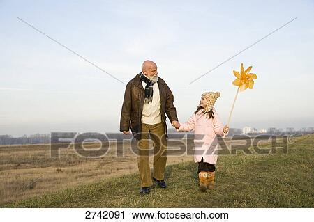 Stock Image - Girl holding pinwheel with her grandfather . Fotosearch