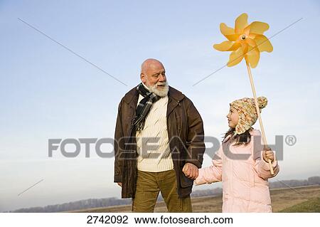 Stock Image - Girl holding pinwheel with her grandfather . Fotosearch