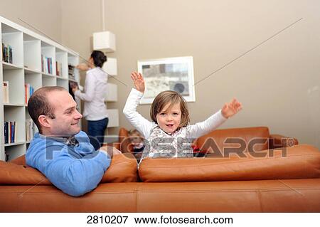Girl playing on couch with her father View Large Photo Image Stock Photo - Girl playing on couch with her father . Fotosearch