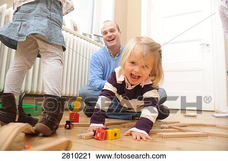 Girl playing with toys and her father playfully pulling her View Large Photo Image Stock Image - Girl playing with toys and her father playfully pulling her . Fotosearch