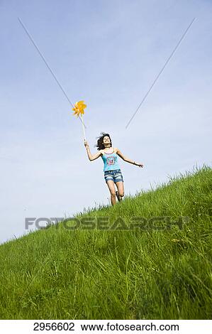 Girl playing with windmill on a meadow View Large Photo Image Stock Image - Girl playing with windmill on a meadow . Fotosearch