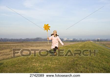 Girl running on landscape with pinwheel View Large Photo Image Stock Photo - Girl running on landscape with pinwheel . Fotosearch