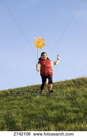 Girl running on landscape with pinwheel View Large Photo Image Stock Photograph - Girl running on landscape with pinwheel . Fotosearch