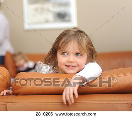Stock Photograph - Girl sitting on couch and smiling . Fotosearch