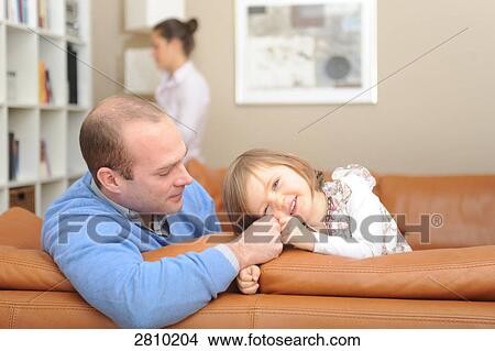Picture - Girl sitting on couch with her father . Fotosearch