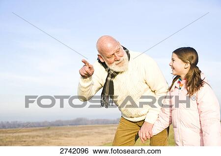 Girl smiling while her grandfather pointing View Large Photo Image Stock Photograph - Girl smiling while her grandfather pointing . Fotosearch
