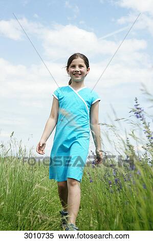 Girl walking through a meadow, low angle view, frontal view View Large Photo Image Stock Photography - Girl walking through a meadow, low angle view, frontal view . Fotosearch