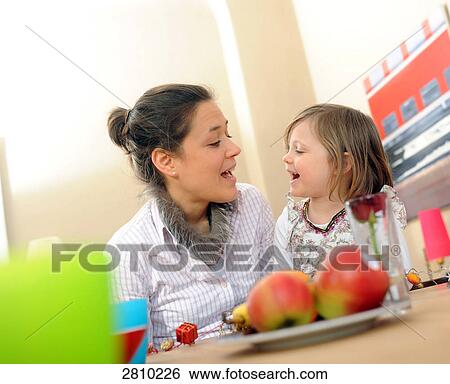Girl with her mother at dining table View Large Photo Image Stock Photograph - Girl with her mother at dining table . Fotosearch