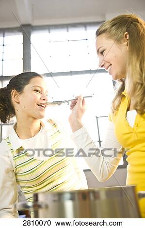 Girl with her mother tasting food in kitchen View Large Photo Image Stock Image - Girl with her mother tasting food in kitchen . Fotosearch