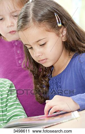 Girls looking at picture book, low angle view  View Large Photo Image Stock Image - Girls looking at picture book, low angle view . Fotosearch