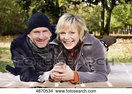 Picture - Happy couple lying on blanket in park . Fotosearch