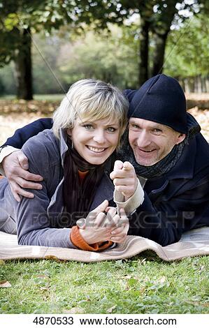 Stock Image - Happy couple lying on blanket in park . Fotosearch