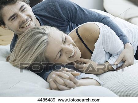 Stock Photo - Happy young couple lying in bed . Fotosearch