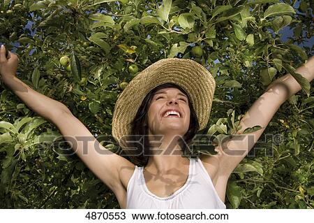 Stock Image - Happy young woman at apple tree . Fotosearch