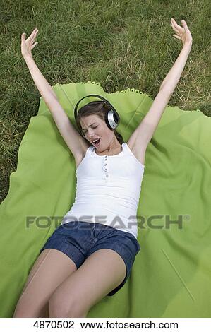 Happy young woman listening to music in meadow View Large Photo Image Stock Image - Happy young woman listening to music in meadow . Fotosearch