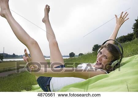 Stock Image - Happy young woman listening to music in meadow . Fotosearch