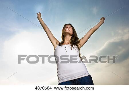 Picture - Happy young woman raising her arms in the air . Fotosearch